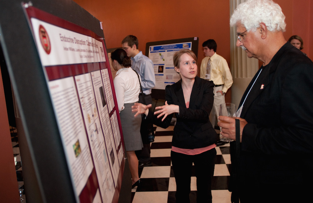 A student presenting her research poster to faculty.