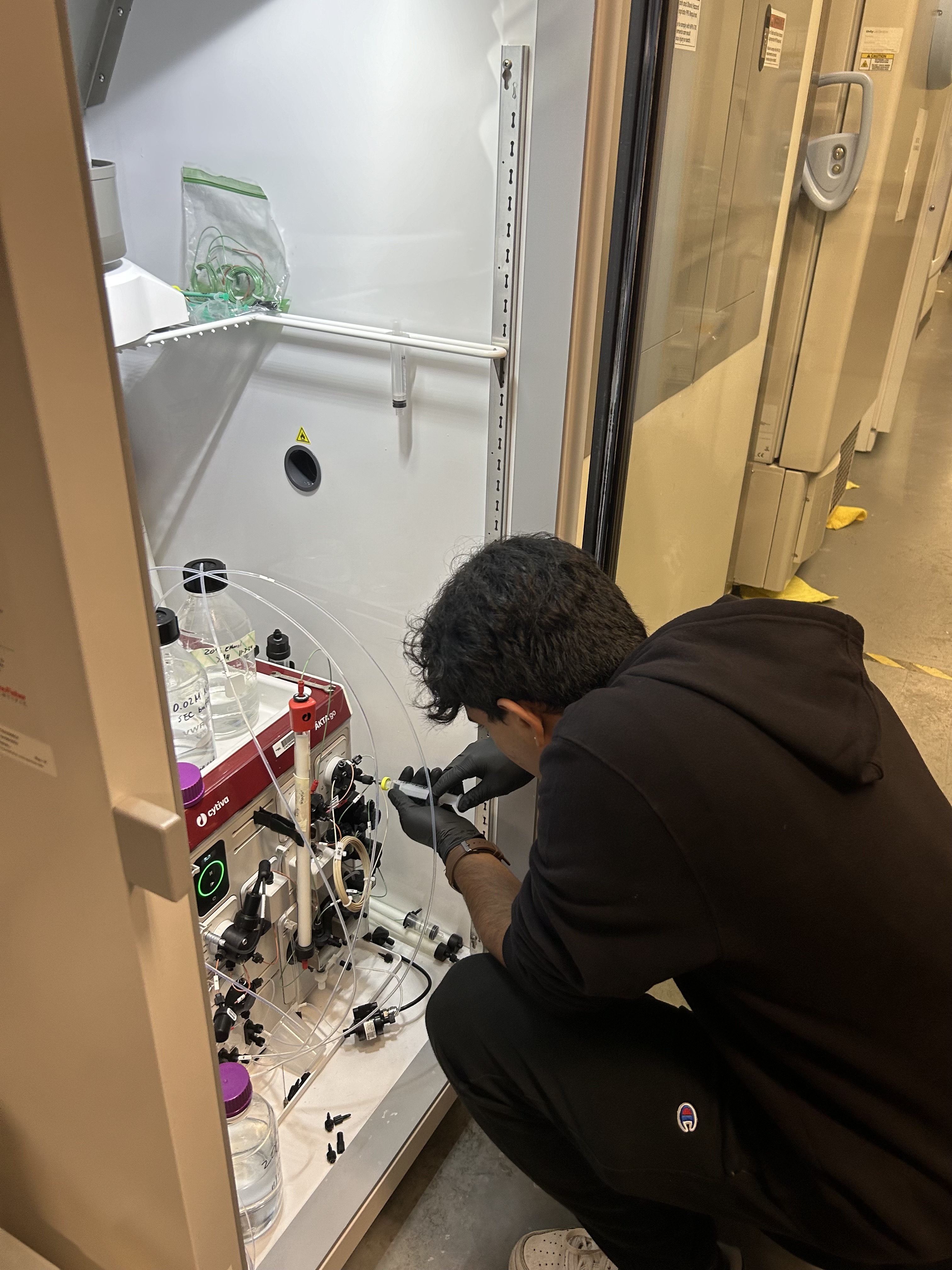 Pranay injects a substance into a lab machine.